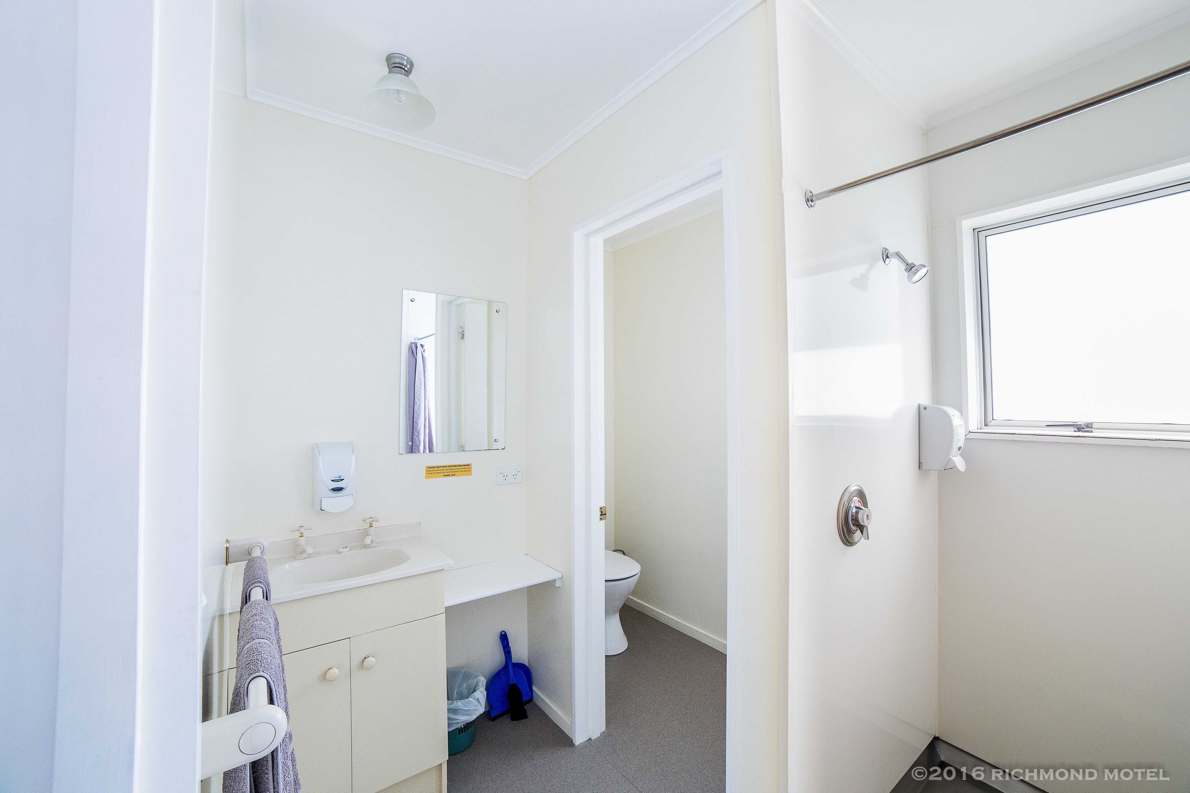 Une salle de bain comprenant des toilettes, un lavabo, un miroir et un espace douche.