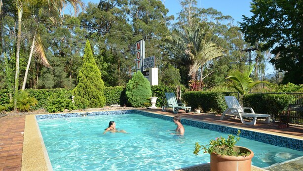 Una piscina rectangular con agua cristalina azul, rodeada por un borde de azulejos y una delimitación de ladrillo.