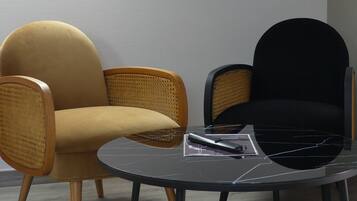 A room with two chairs, one yellow and one black, and a small table with a remote control and a magazine.