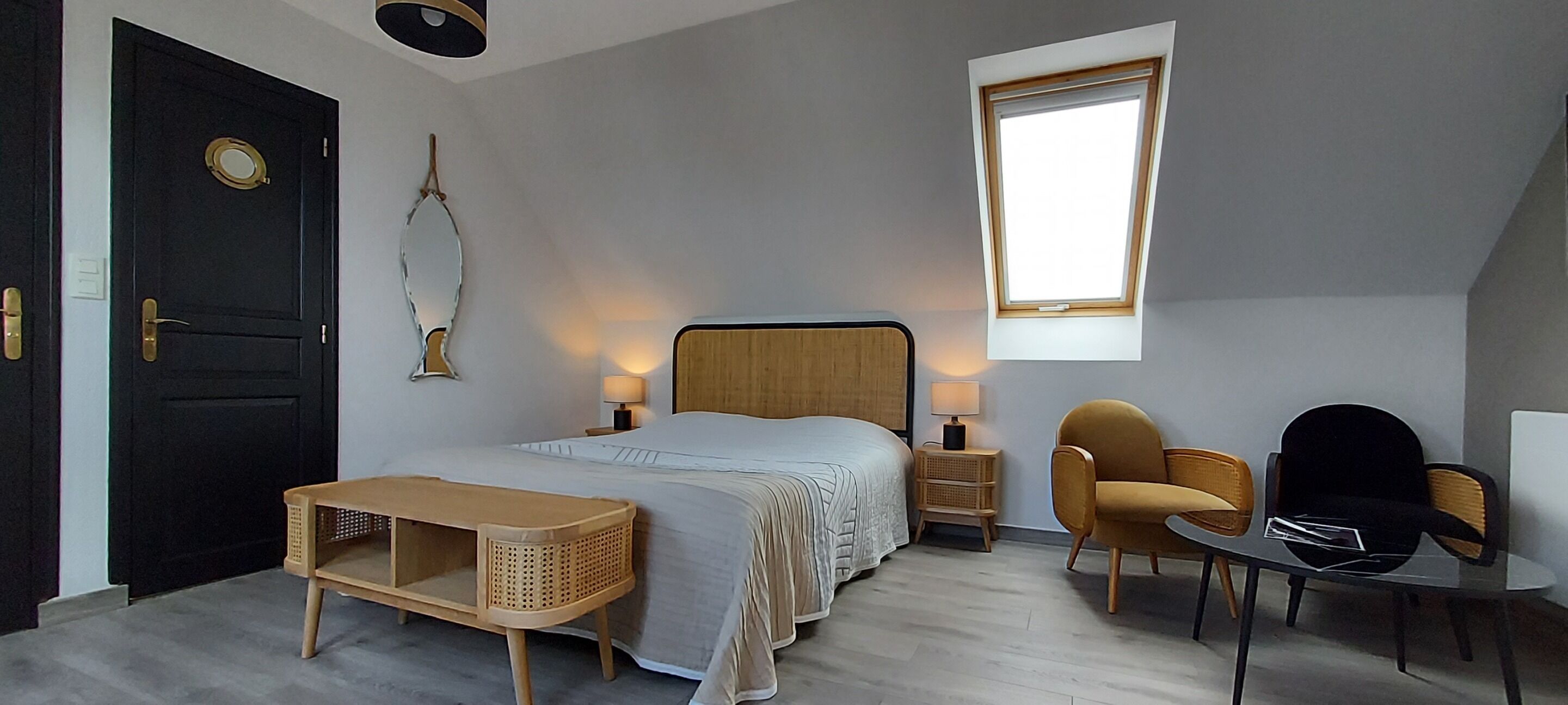 A bedroom with a bed, bedside tables, a lamp, a chair, a small table, a mirror, and a window.