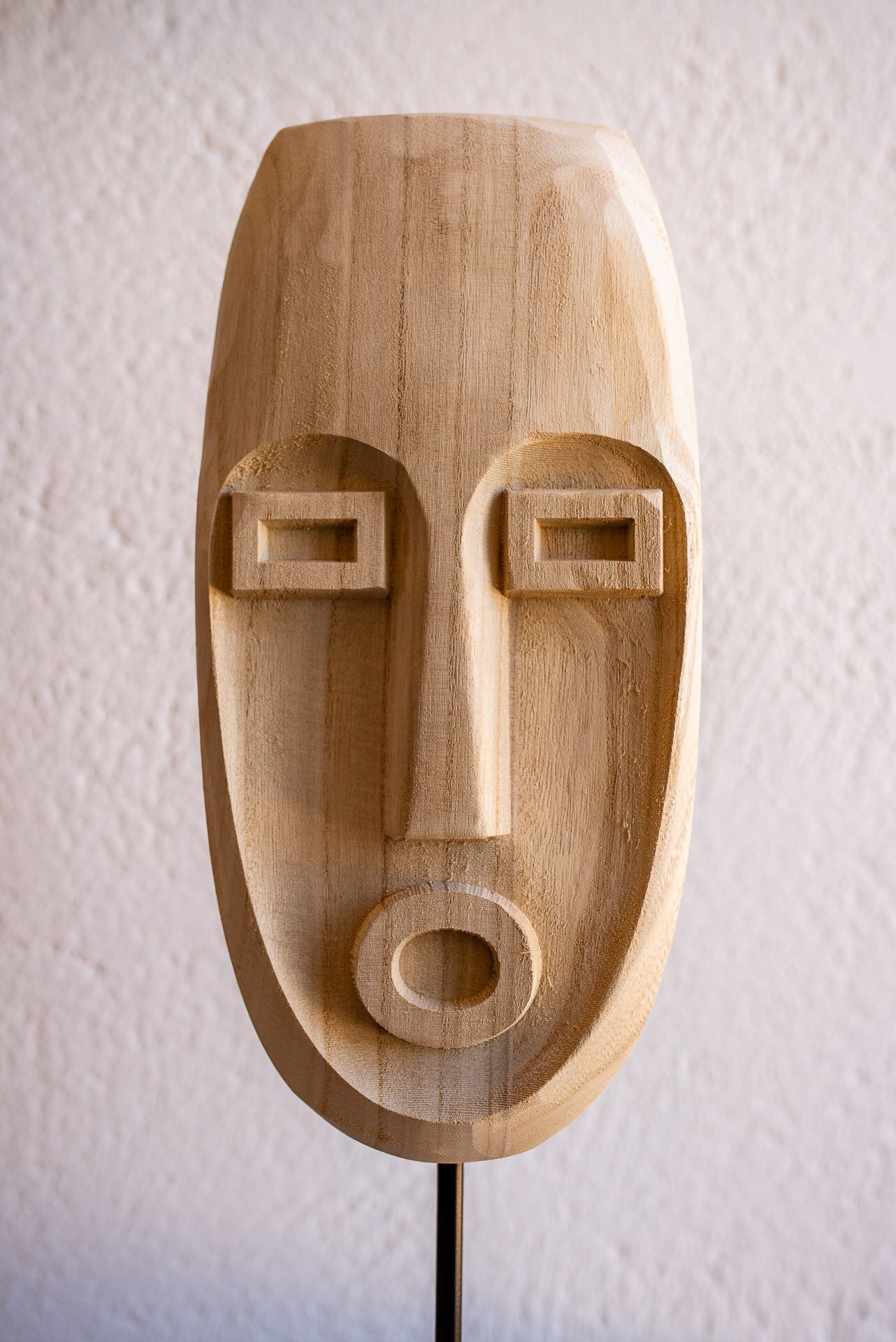 A wooden mask with a simple, geometric face design.