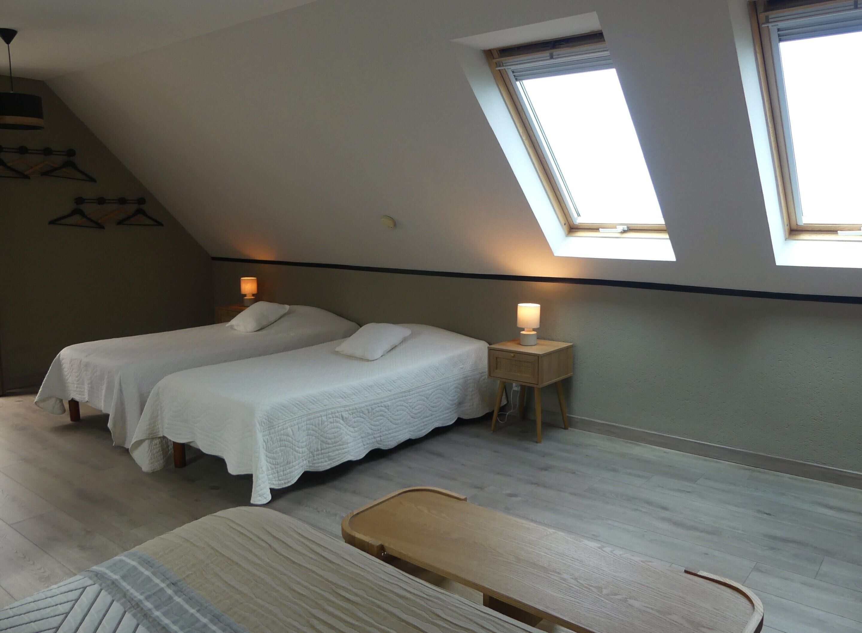 A bedroom with two beds, a bench, and a skylight.