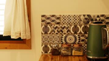 A kitchen with a gas stove, a kettle, and a patterned backsplash.