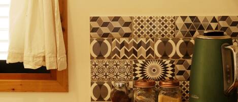 A kitchen with a gas stove, a kettle, and a patterned backsplash.