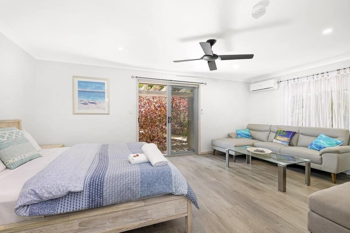 Un dormitorio moderno con cama, sofá, una mesita de centro y ventilador de techo.