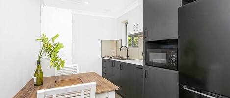 A modern kitchen with dark cabinetry, a stainless steel refrigerator, and a microwave.