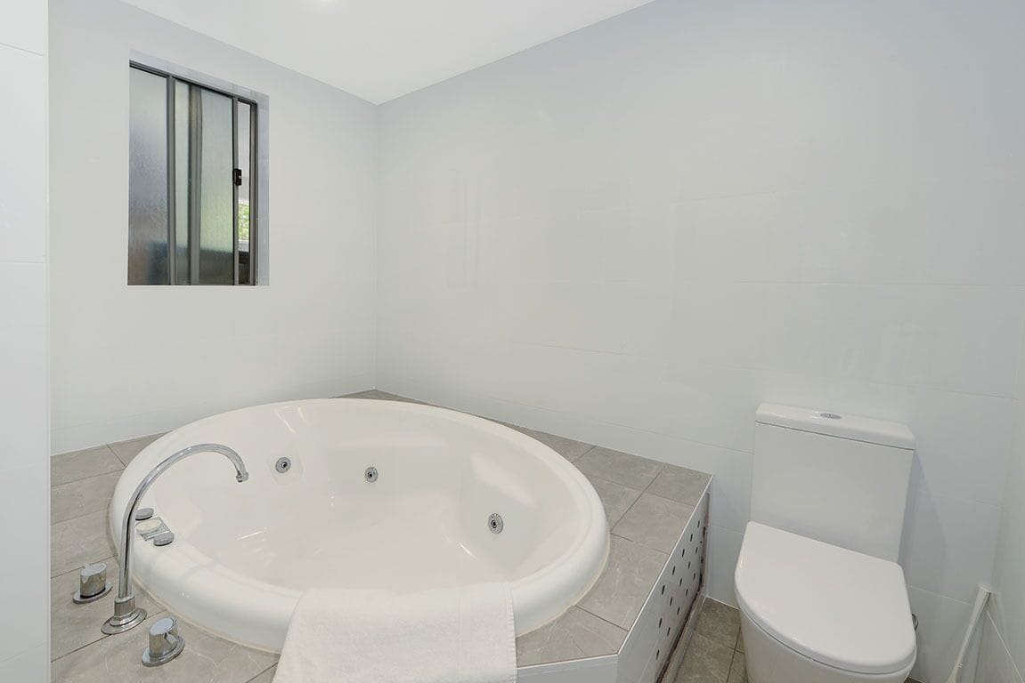Une salle de bain moderne avec une baignoire sur pieds, des toilettes et une fenêtre.
