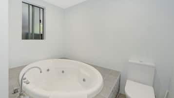 A modern bathroom with a freestanding bathtub, a toilet, and a window.