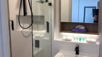 A modern bathroom with a glass-enclosed shower, a vanity with a sink, and a mirror above the vanity.
