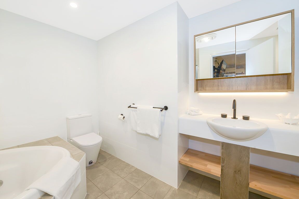 A modern bathroom with a bathtub, toilet, and sink.