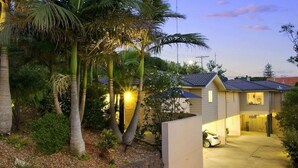 A residential house with a garage, surrounded by palm trees and a garden. - Tiarri Terrigal (Terrigal)