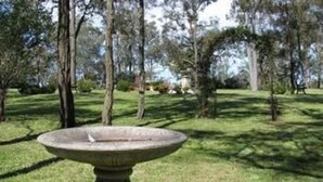 Un abrevadero para pájaros en un parque con árboles y césped.