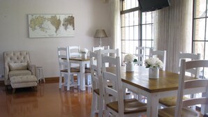 Un comedor con una mesa de madera y sillas blancas, un mapa en la pared y una lámpara.