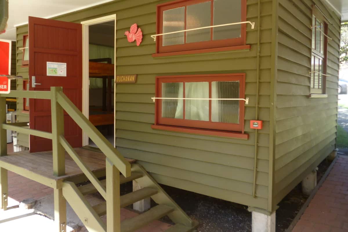 Un bâtiment à deux étages avec une porte et des fenêtres rouges, un escalier en bois et une enseigne sur laquelle on peut lire « BUCHANAN ».