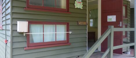 A green building with two windows, a wooden staircase, and a door labeled "WESTTRAY".