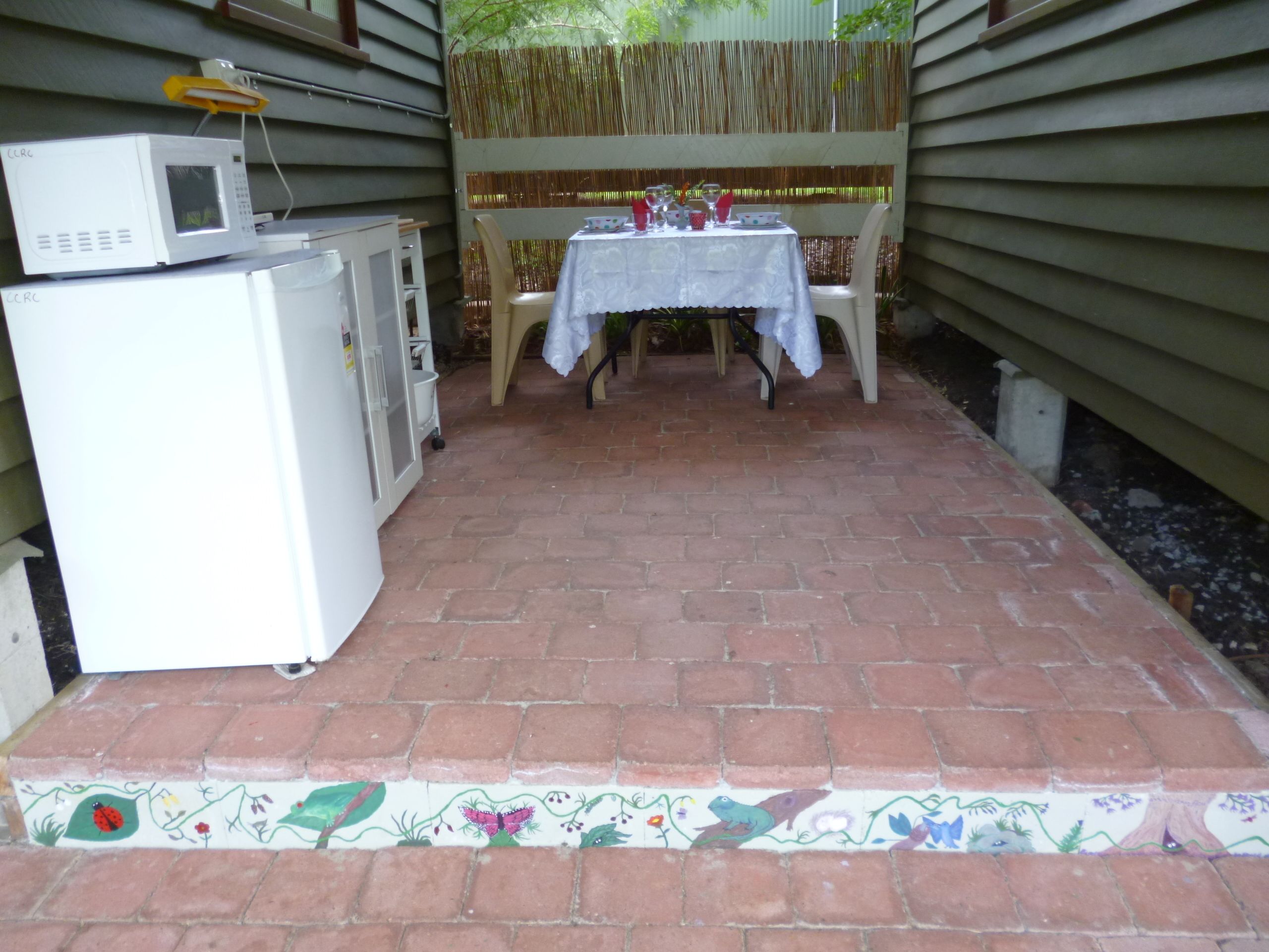Een terras met een eettafel, een koelkast en een magnetron.