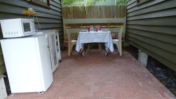 Een terras met een eettafel, een koelkast en een magnetron.
