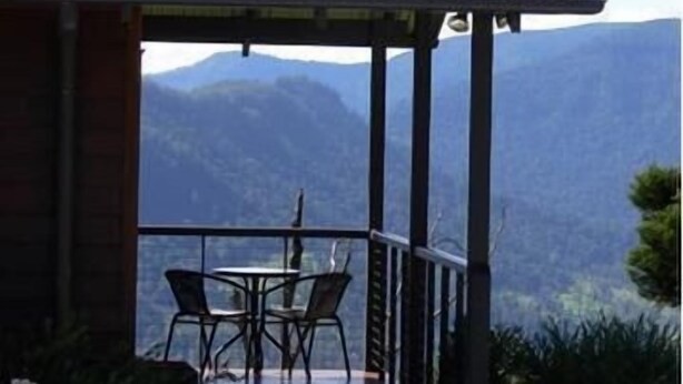 Un espacio de estar al aire libre cubierto con una mesa y sillas, con vistas a un paisaje montañoso.