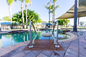 A pool with a wooden deck and metal railings, surrounded by palm trees and a covered seating area. - Murray Downs Resort (Murray Downs)