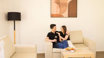 Ein modernes Wohnzimmer mit einem beigen Sofa, einem Couchtisch mit einer Speisenplatte und einer Stehlampe.
