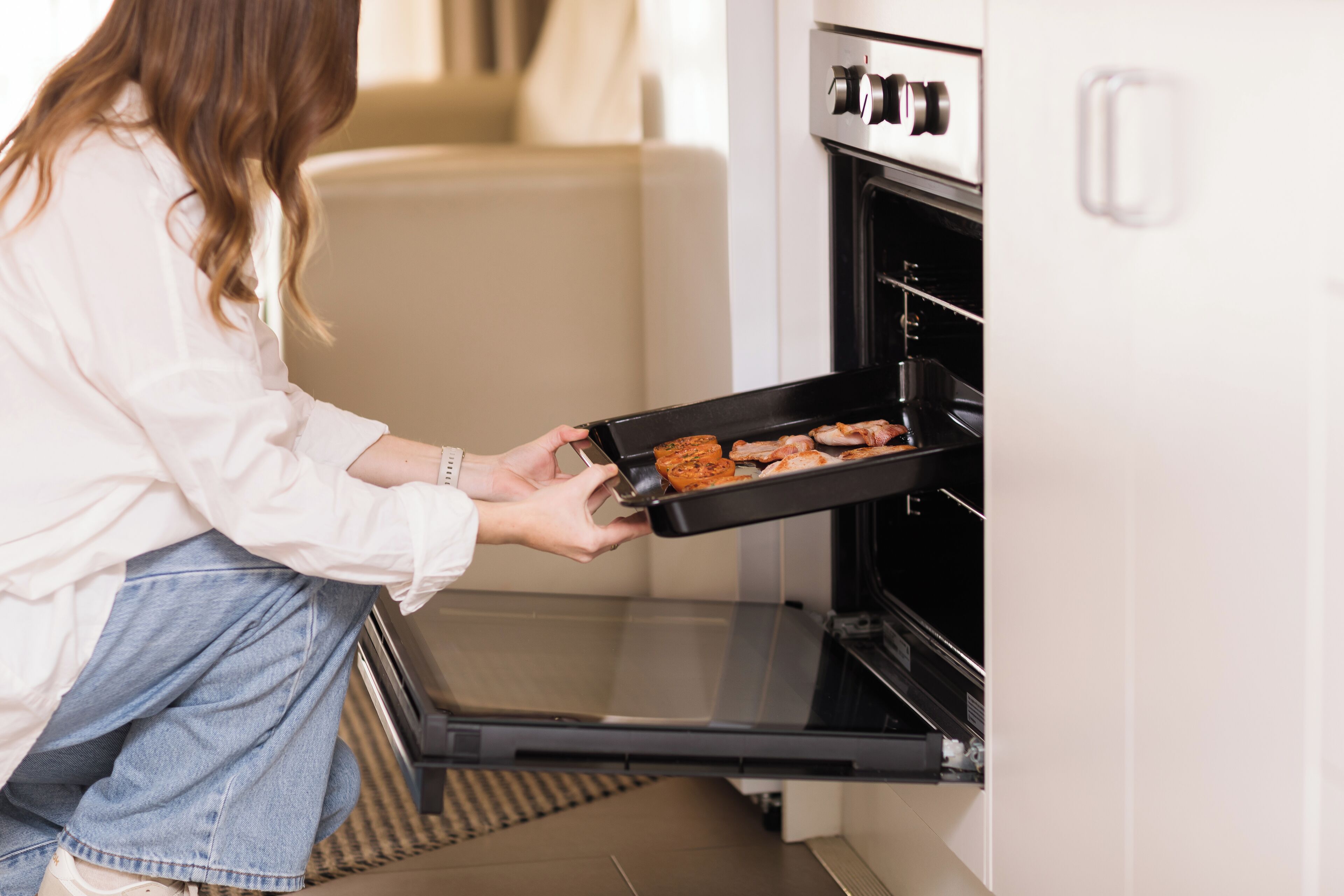 A person placing a tray of food into an oven.