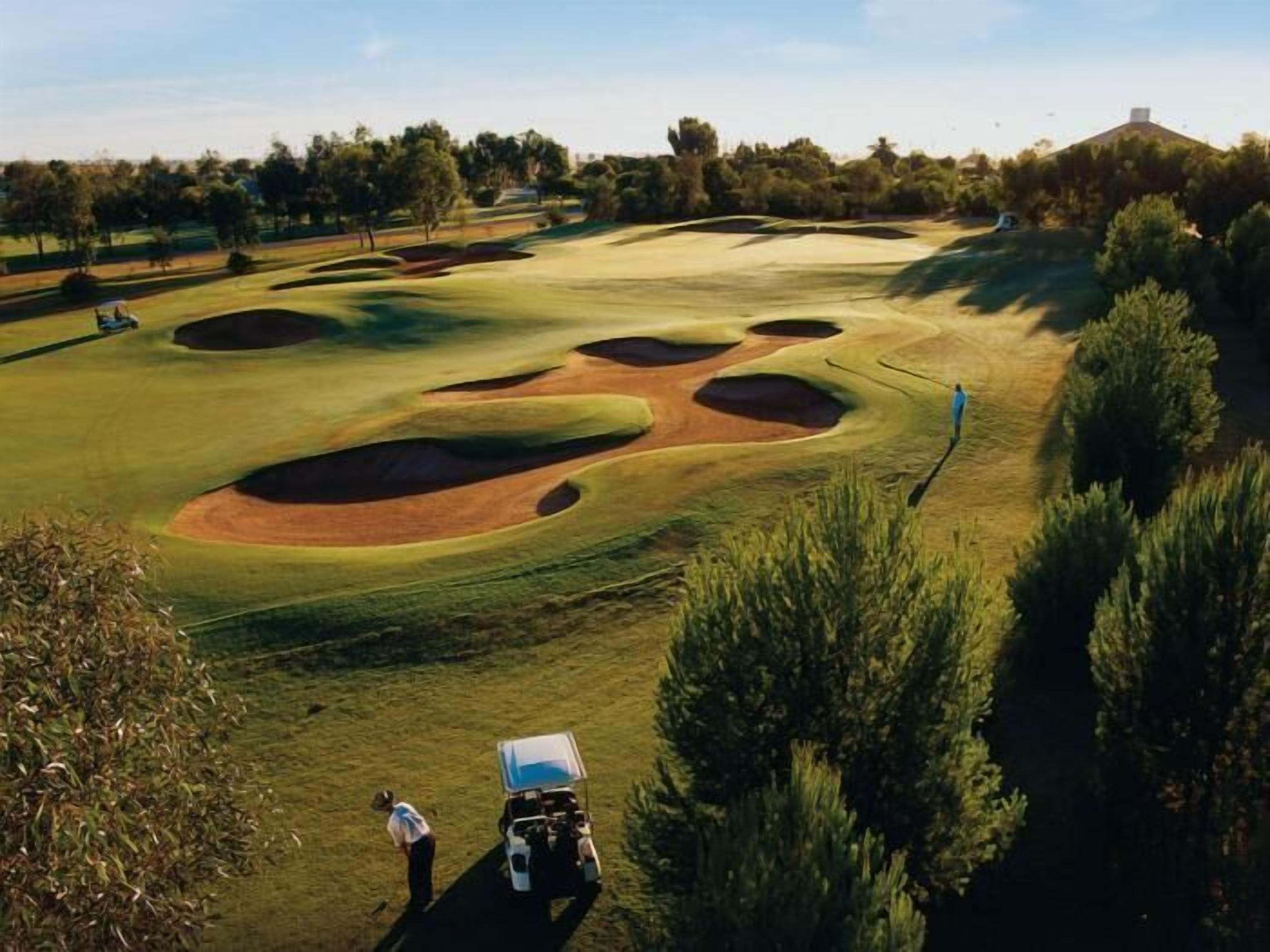 A golf course with bunkers and a cart.