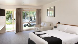 A hotel room with a bed, a sofa, a TV, and a window with curtains. - Murray Downs Resort (Murray Downs)