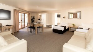 A hotel room with a bed, two white sofas, a dining table with chairs, a TV mounted on the wall, and a large mirror. - Murray Downs Resort (Murray Downs)