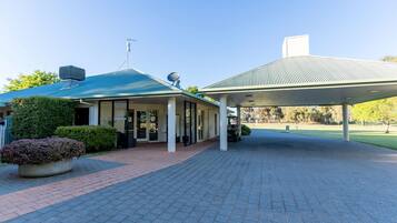 Guests enter through a covered walkway to a modern building surrounded by lush greenery.