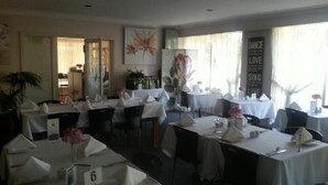 A dining area with tables set for service, numbered placemats, and a wall with motivational posters. - Yass Motel (Yass)