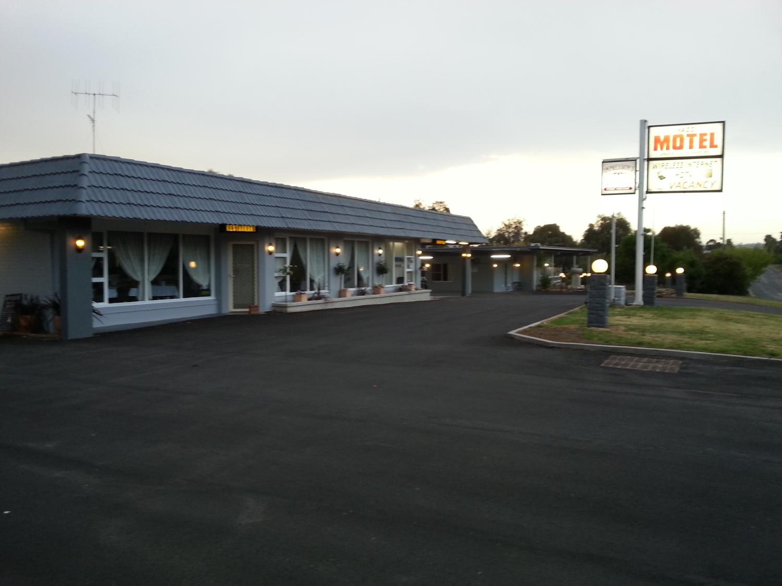 A motel with a single-story structure, a covered parking area, and a sign indicating the presence of a wireless internet facility.