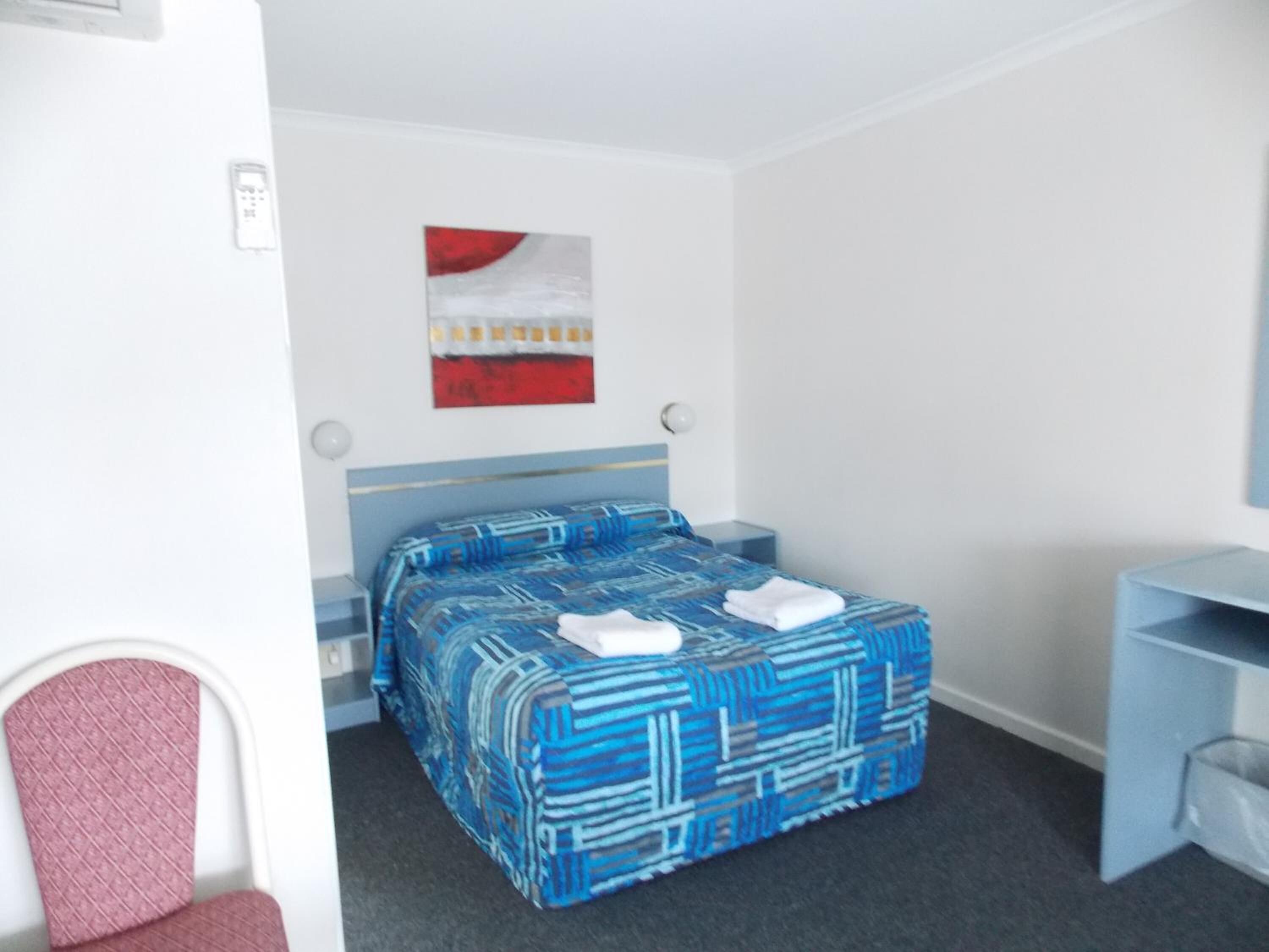 A hotel room with a bed, a desk, and a chair.
