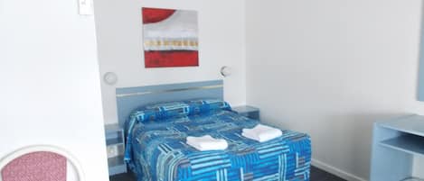 A hotel room with a bed, a desk, and a chair.