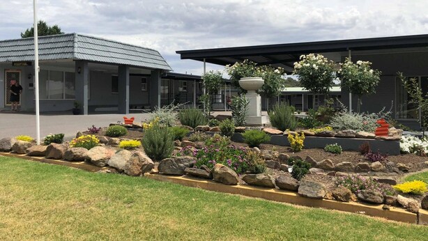 A modern building with a reception area, a garden with various plants and a central water feature, and a flagpole. - Yass Motel (Yass)
