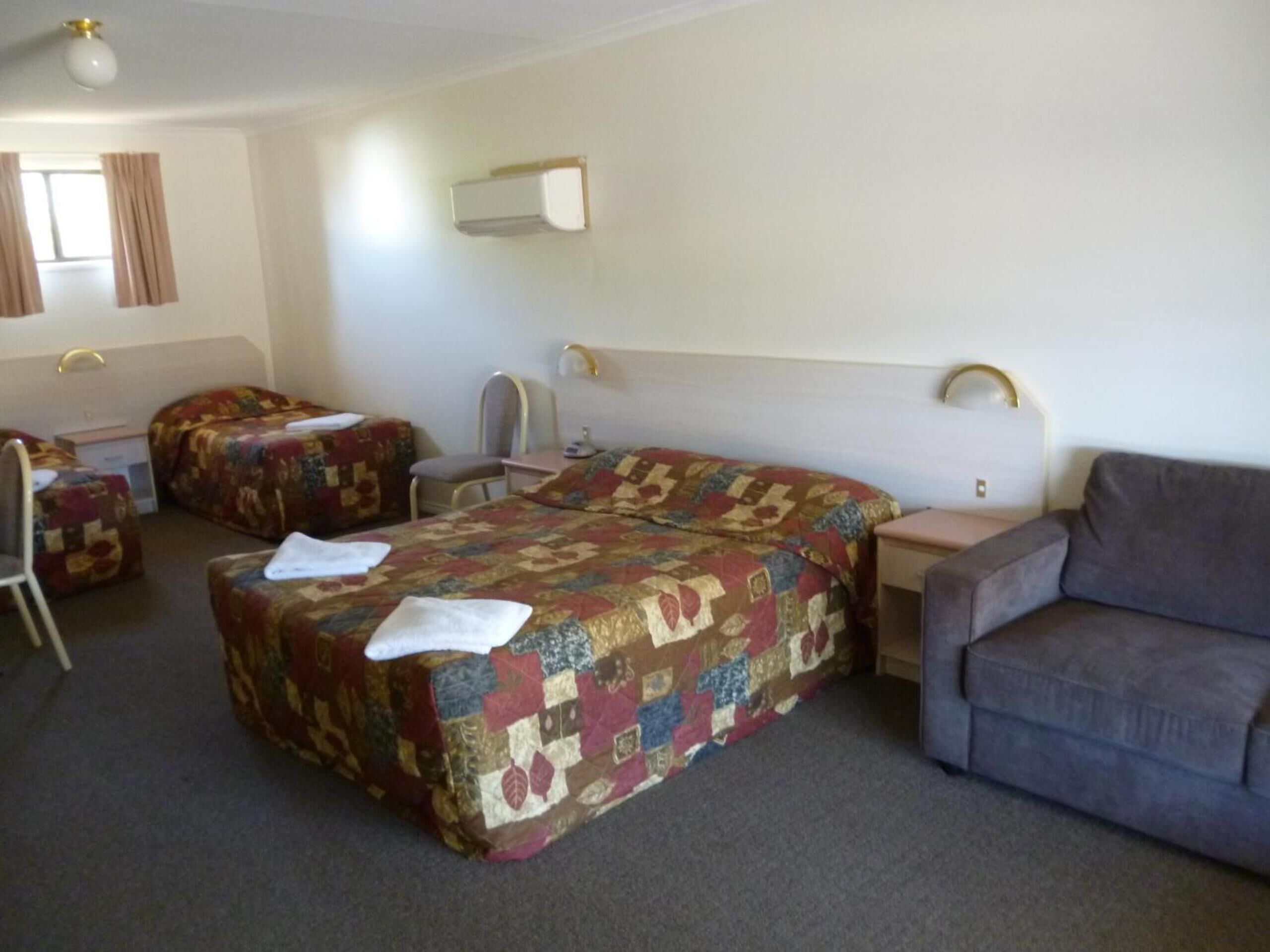 Habitación de hotel con dos camas, un escritorio, una silla y un sofá.