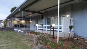 A modern house with a covered porch, a car parked in the driveway, and a well-maintained garden with a stone border and small plants. - Yass Motel (Yass)
