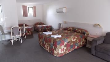 A hotel room with two beds, a desk, and a chair.