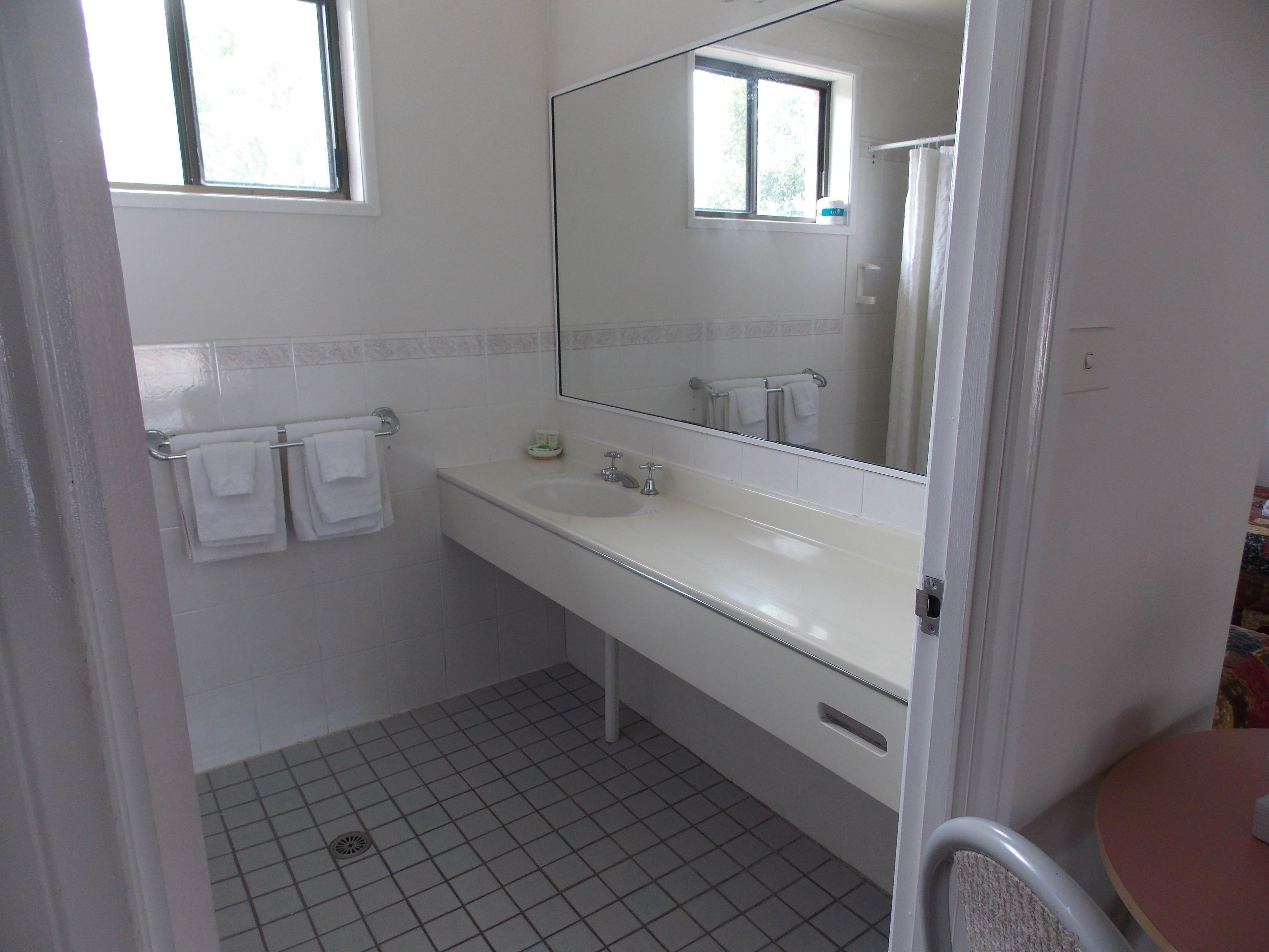 Une salle de bain avec un lavabo blanc, un miroir et un sol carrelé.