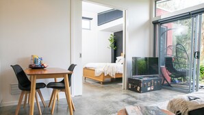 Una sala moderna con comedor, cama y puerta corrediza de vidrio que da a un balcón.
