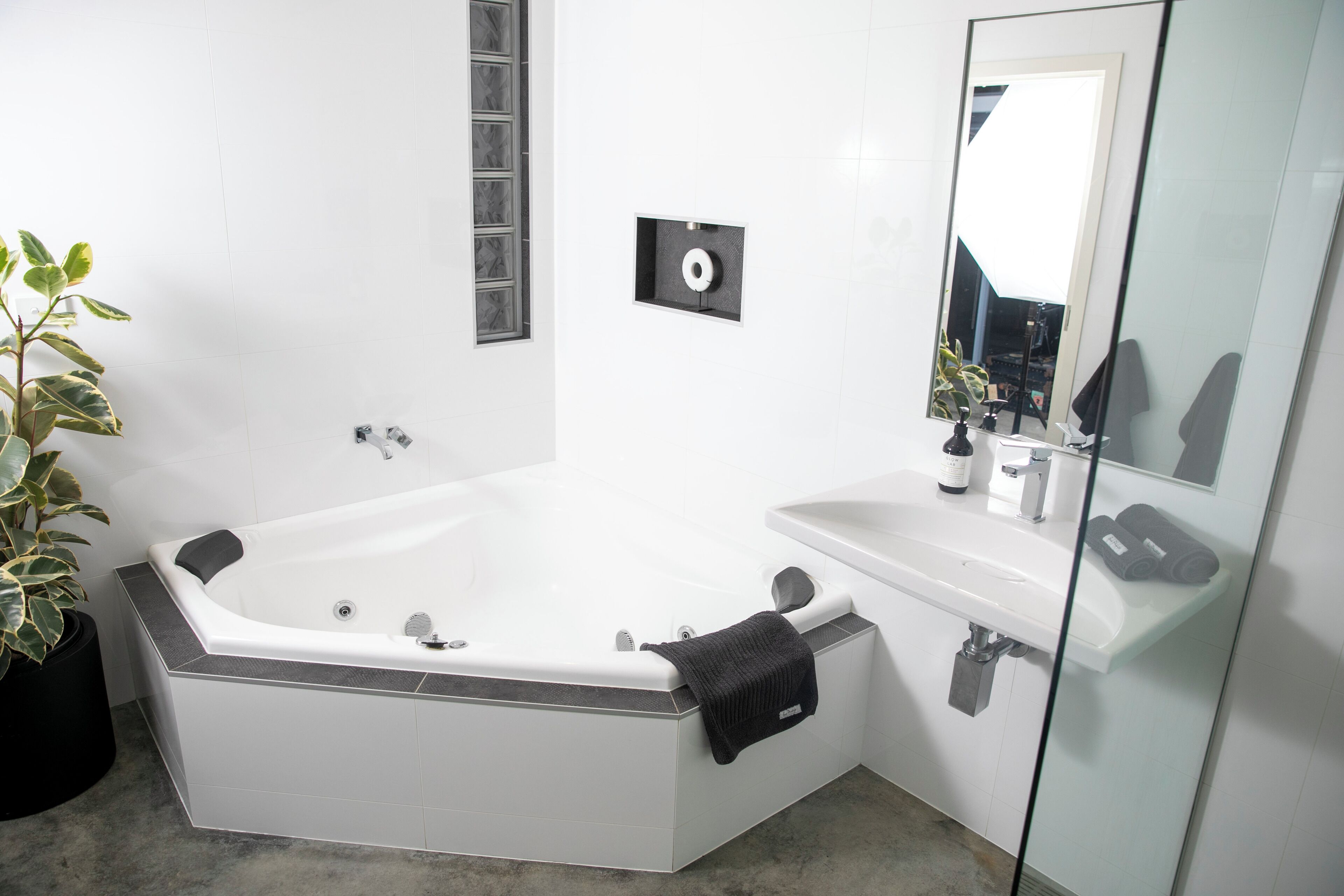Un baño moderno con una bañera en esquina, cabina de ducha con vidrio y un espejo grande.