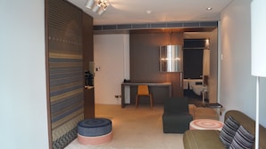 A modern hotel room with a sofa, ottoman, and a small desk area. - Valentine On George (Haymarket)