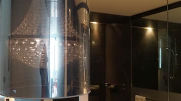A modern bathroom with a large mirror, a double sink, and a shower area.