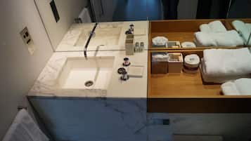 A bathroom with two sinks, a mirror, and a wooden vanity with towels.