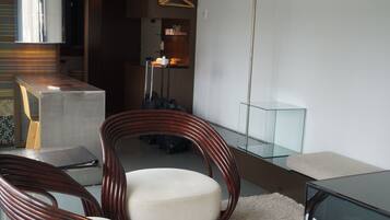 Un salón moderno con dos sillas de madera, una mesa de centro de vidrio y una alfombra mullida blanca.