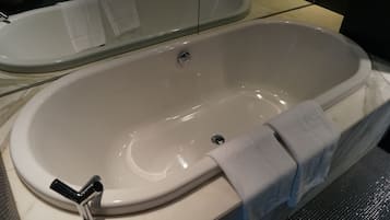 A white freestanding bathtub with a chrome faucet and a towel draped over the side.