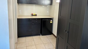 A compact kitchen with dark cabinetry, a small countertop, and a dishwasher. - Hi Way Eight Motor Inn (Stawell)