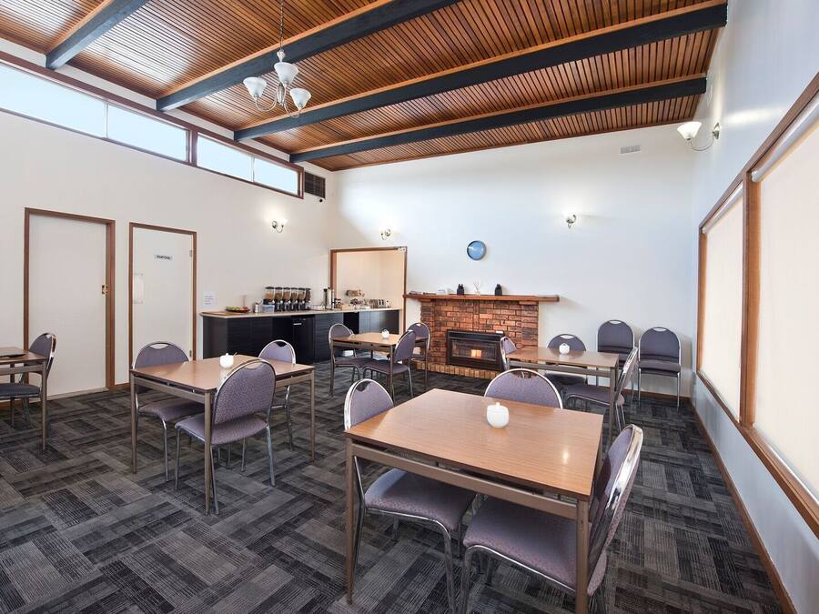 Uma sala de conferência com uma mesa comprida, várias cadeiras, uma área de cozinha e uma lareira.