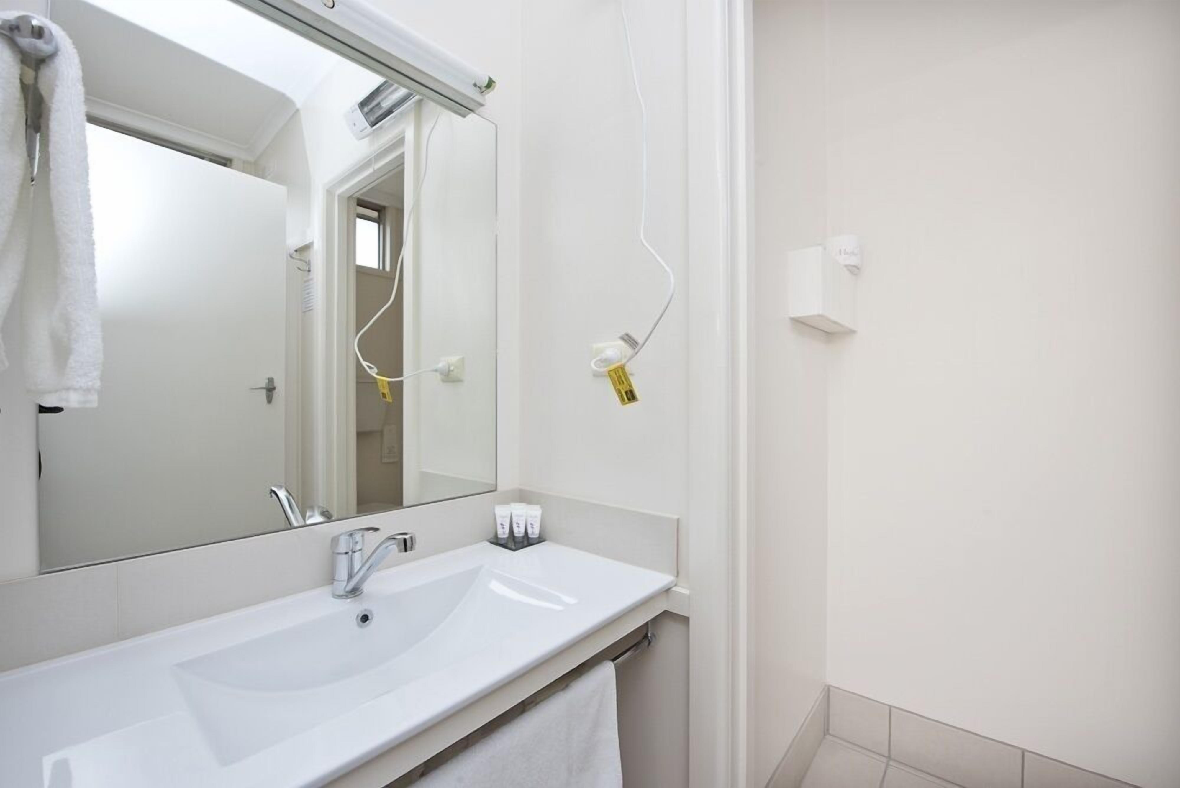 Une salle de bain moderne avec un lavabo blanc, un miroir et un porte-serviettes.