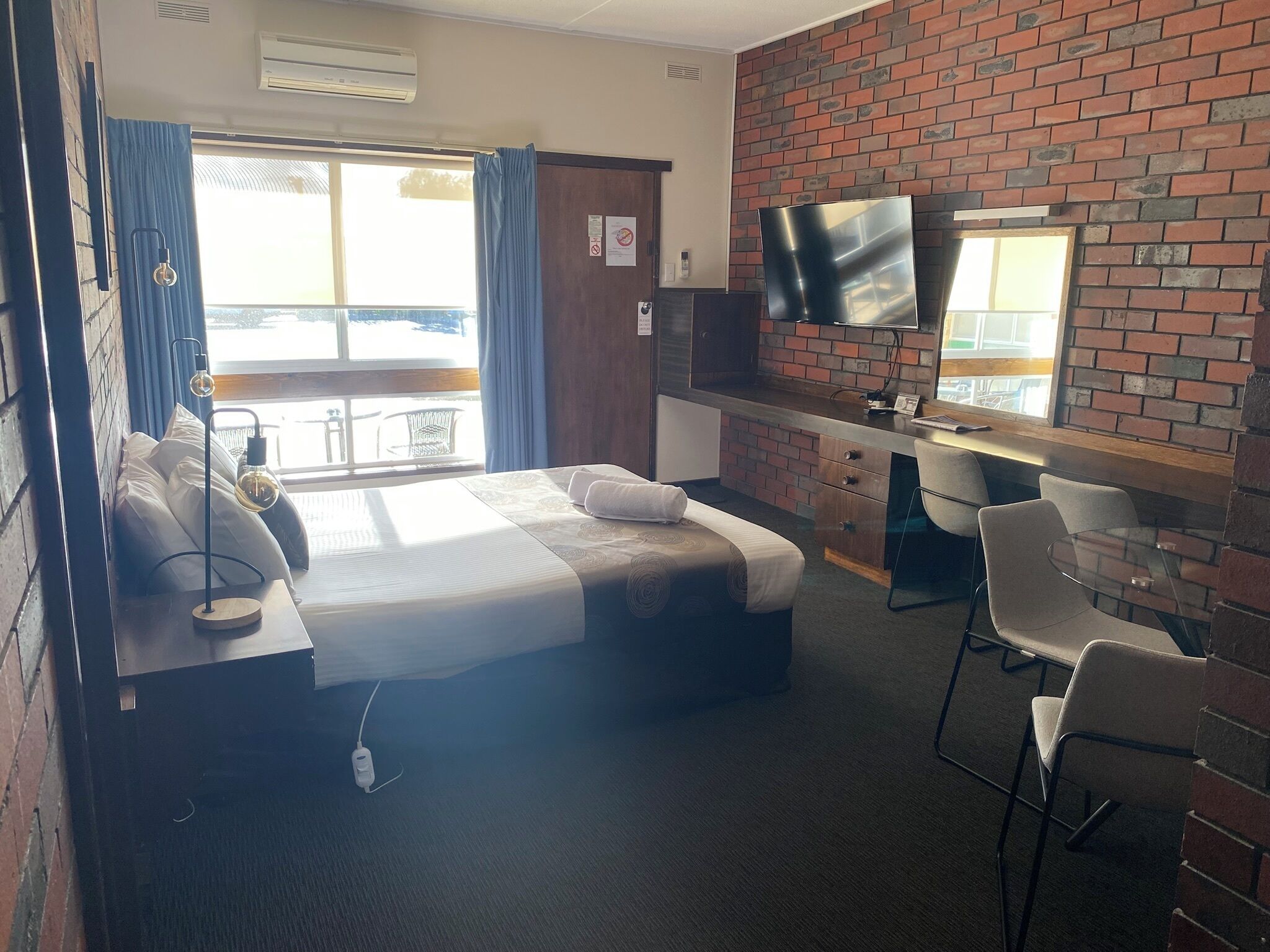 Una habitación de hotel con cama, escritorio, sillas y televisión.
