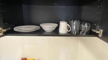 A kitchen counter with white plates, bowls, a mug, and glassware.